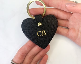 May include: Black leather heart-shaped keychain with a gold key ring and the initials "CB" embossed in gold.