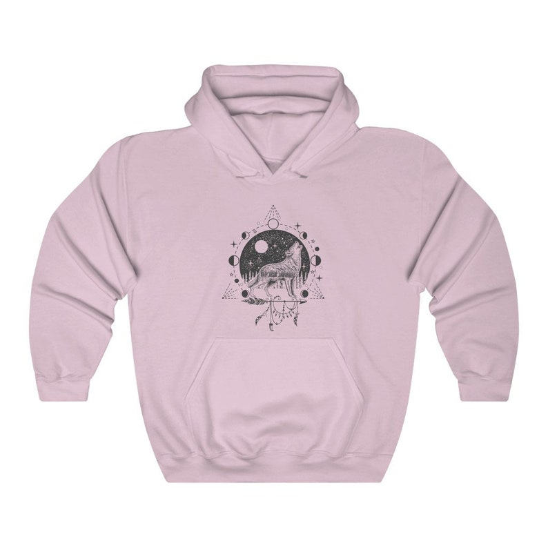 Pode incluir: Uma camisa de moletom rosa com capuz com uma estampa gr&aacute;fica em preto e branco de um lobo uivando para a lua. O gr&aacute;fico tamb&eacute;m inclui um ciclo de fases lunares, um tri&acirc;ngulo e um apanhador de sonhos.