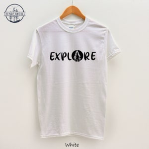 Pu&ograve; includere: Maglietta bianca con testo nero che dice "EXPLORE" con un pino all'interno di un cerchio.