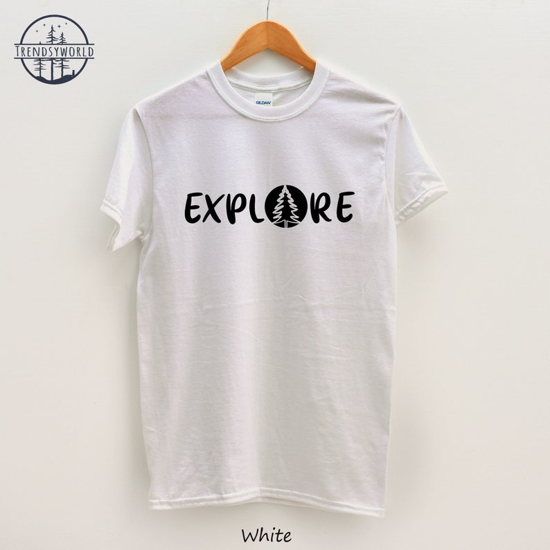 Pu&ograve; includere: Maglietta bianca con testo nero che dice "EXPLORE" con un pino all'interno di un cerchio.
