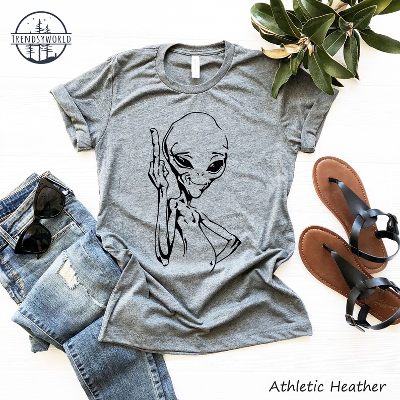 K&ouml;nnte beinhalten: Ein graues T-Shirt mit einer schwarzen Alien-Grafik, die den Mittelfinger zeigt. Der Text "Athletic Heather" ist unter der Grafik gedruckt.