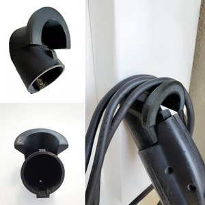 May include: A black electric vehicle charging cable with a hook for hanging on a wall. The cable is labeled "60Hz 15A 12V/24V/48V - MADE IN THE EU".