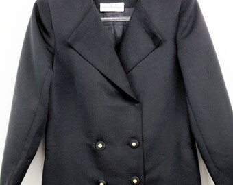May include: A black blazer with a double-breasted closure and gold buttons. The blazer has a long, fitted silhouette and a pointed collar. The label "Noren Boutique" is visible on the inside of the collar.