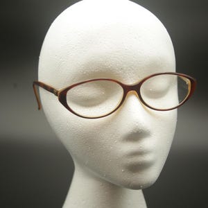 Könnte beinhalten: Eine braune, ovale Brille mit klaren Gläsern.