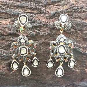 Pode incluir: Um par de brincos de prata com design floral. Os brincos são adornados com pequenos diamantes e detalhes pretos. Os brincos têm forma de lágrima e estão suspensos de uma pequena parte superior redonda em forma de diamante.