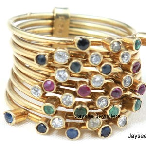 Può includere: Un anello d'oro con più bande incastonate con una varietà di pietre preziose colorate, tra cui zaffiri, rubini, smeraldi e diamanti. L'anello è progettato con un gruppo di pietre preziose incastonate in uno schema casuale.