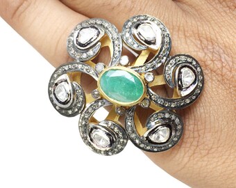 May include: A gold ring featuring a green emerald gemstone surrounded by smaller diamonds. The ring has a floral design with intricate details.