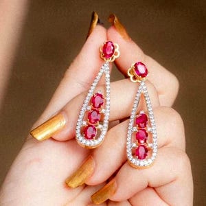 May include: A set of three ceramic mugs with a speckled, cream-colored glaze. Each mug features a different hand-painted floral design in shades of blue, green, and yellow. The mugs have a simple, rounded shape and a comfortable handle.