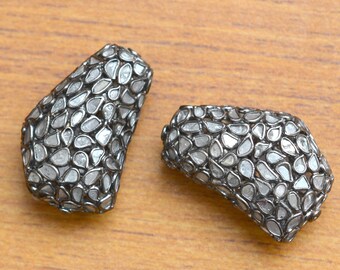 May include: Two silver earrings with a geometric shape, each earring is covered in small, clear, faceted diamonds.