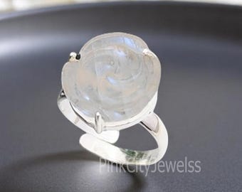 May include: A silver ring with a white moonstone carved into the shape of a rose.