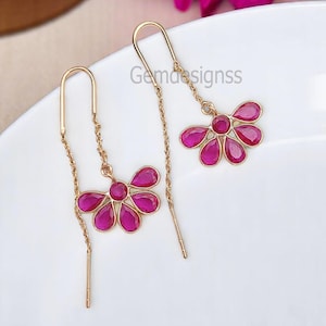 Puede incluir: Un par de pendientes de oro con un diseño de flor rosa. Cada pendiente presenta un racimo de piedras preciosas rosas en forma de flor.