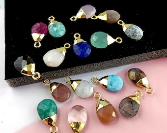 May include: Assortment of 15 gemstone pendants with gold-plated caps. The gemstones are in various shapes and colors, including black, blue, green, pink, red, and white.