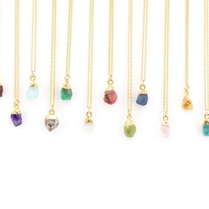May include: A collection of 10 gold necklaces with different coloured gemstone pendants. The gemstones include amethyst, aquamarine, emerald, ruby, sapphire, rose quartz, and green aventurine.