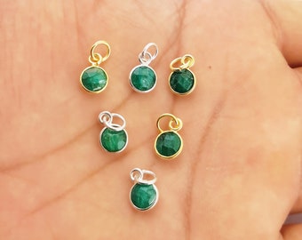 May include: Six green gemstone charms with gold and silver settings. The charms are round and have a smooth, polished finish. They are perfect for adding a touch of elegance to jewelry projects.