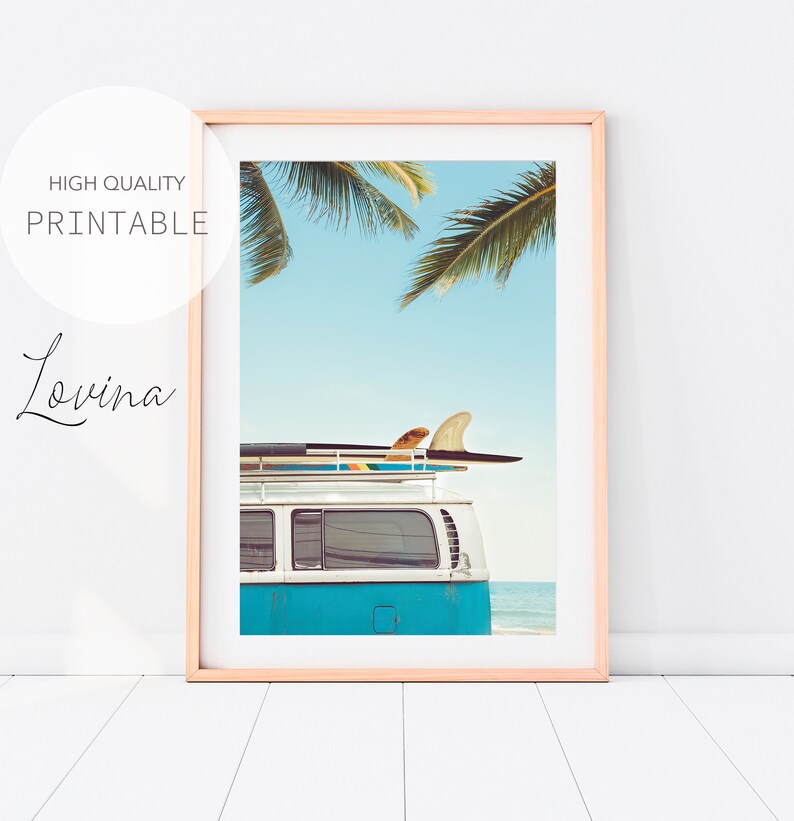 May include: A blue vintage van with a surfboard on the roof, parked on a beach with palm trees in the background.