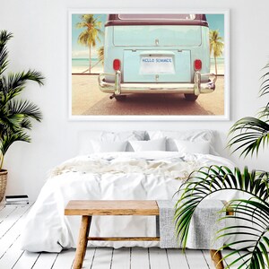 Pode incluir: Uma van vintage azul e branca com uma placa que diz "HELLO SUMMER" estacionada em uma praia com palmeiras ao fundo.