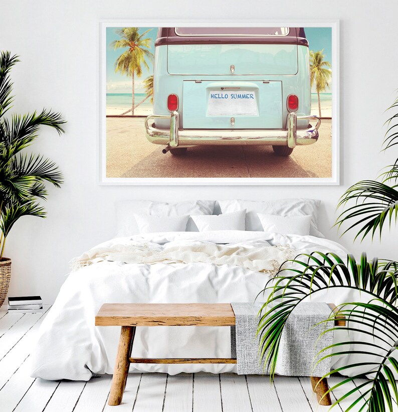 Pode incluir: Uma van vintage azul e branca com uma placa que diz "HELLO SUMMER" estacionada em uma praia com palmeiras ao fundo.
