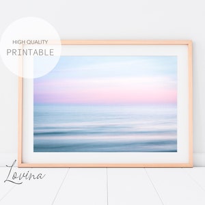 May include: A framed photograph of a seascape with a soft, pink and blue gradient sky and a blurred, abstract ocean. The image is titled "Lovina" in a cursive font.