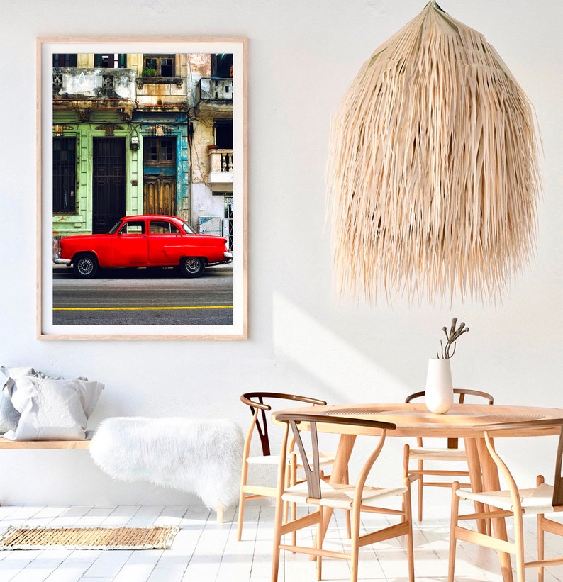 May include: A framed photograph of a red vintage car parked in front of a colorful building in Havana, Cuba. The building has green and blue paint and a wooden door. The car is a classic American model with chrome accents.