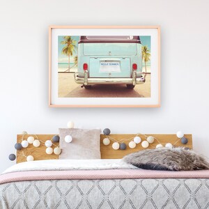 Pode incluir: Uma fotografia vintage emoldurada de uma van azul com uma placa que diz "HELLO SUMMER" estacionada em uma praia com palmeiras ao fundo.