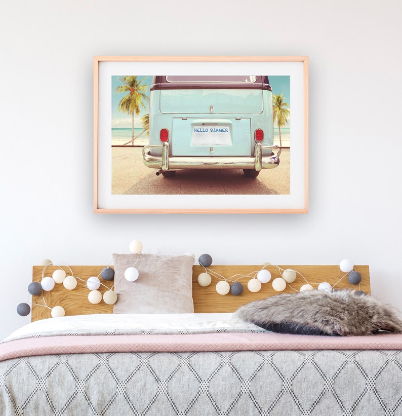 Pode incluir: Uma fotografia vintage emoldurada de uma van azul com uma placa que diz "HELLO SUMMER" estacionada em uma praia com palmeiras ao fundo.