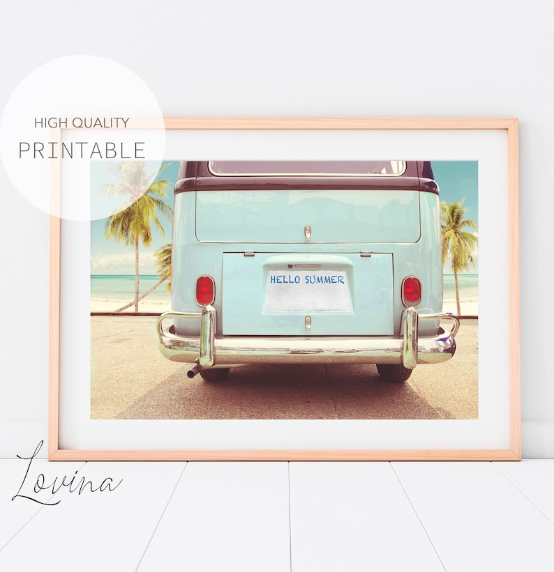 Pode incluir: Uma van vintage azul e branca com uma placa que diz "HELLO SUMMER" estacionada em uma praia com palmeiras ao fundo.