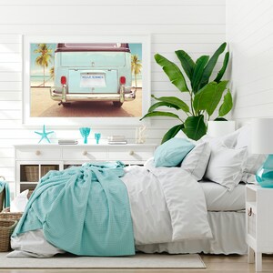 Pode incluir: Um quarto branco com uma cama, uma c&ocirc;moda branca e uma impress&atilde;o emoldurada de uma van vintage azul com as palavras "Hello Summer" na placa. A van est&aacute; estacionada em uma praia com palmeiras ao fundo.