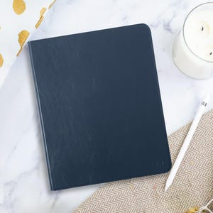 May include: A dark blue leather-bound notebook with the word "fifty" embossed on the front cover.
