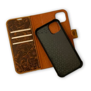 May include: A brown leather phone case with a floral embossed design. The case has a flap that folds over the phone and a slot for credit cards. The phone case is open, revealing a black phone case with a honeycomb pattern.