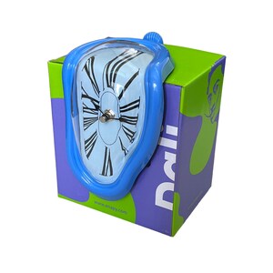 May include: A blue melting clock with Roman numeral markings on a white face, sitting on a green, purple, and white box with the word "Dali" printed on the side. The box has the website "www.enapy.com" printed on the bottom.