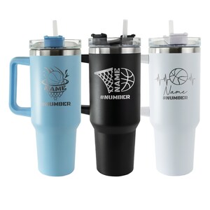 May include: Three stainless steel travel mugs with handles and lids. The mugs are blue, black, and white. Each mug has a basketball design and the text "Name #Number".