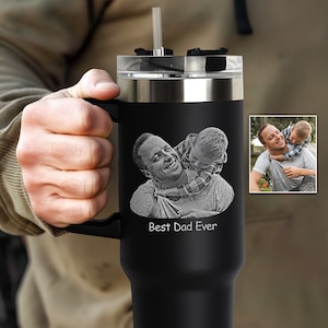May include: Black stainless steel travel mug with a black handle and a straw. The mug has an engraved image of a father and son with the text "Best Dad Ever".