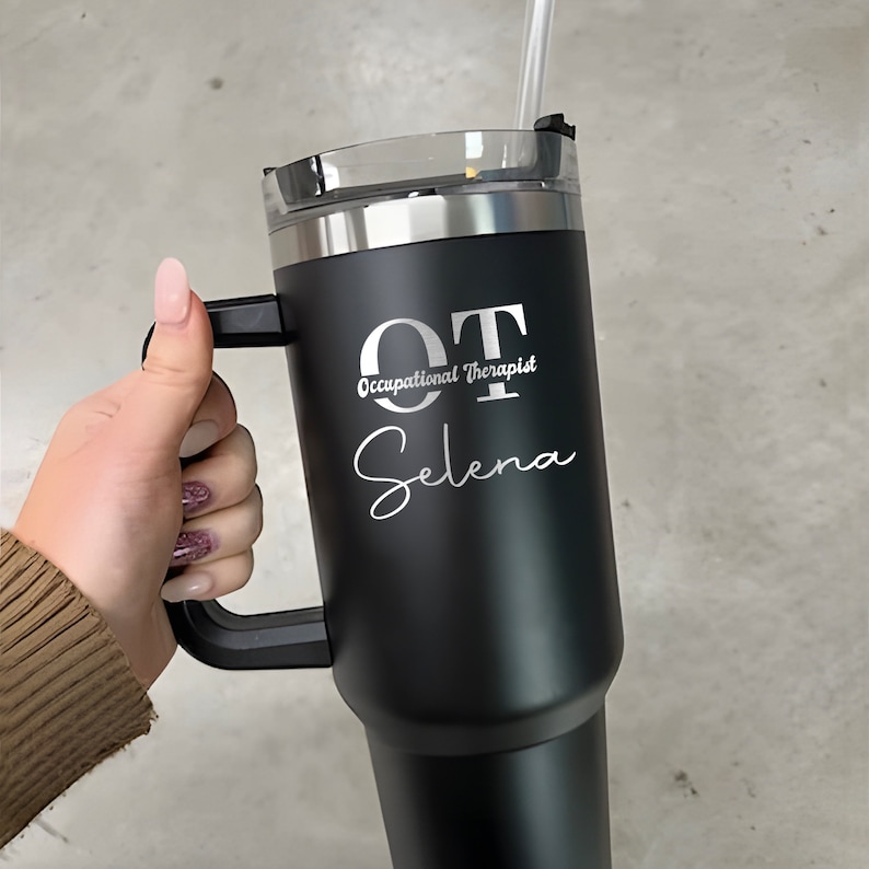 Pu&ograve; includere: Tazzina da viaggio in acciaio inox nero con manico nero. La tazza ha un coperchio argentato ed &egrave; incisa con il testo "OT Occupational Therapist Selena".