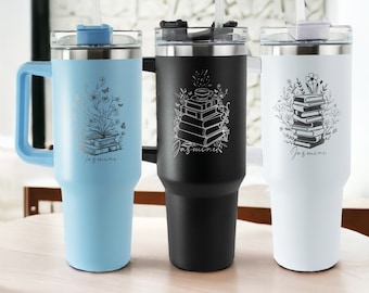 May include: Three stainless steel travel mugs with lids and straws. The mugs are blue, black, and white. Each mug has a design of a stack of books with flowers and butterflies. The name "Jasmine" is engraved on each mug.