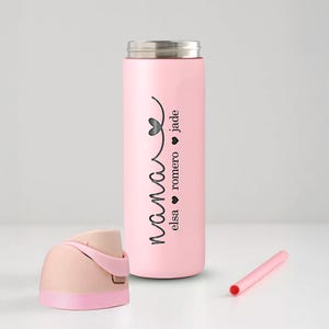 May include: A pink insulated water bottle with a silver lid, a pink straw, and a detached pink and beige lid. The bottle has the word "nana" in a script font, with the names "elsa", "romero", and "jade" printed vertically.