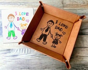 Pode incluir: Uma bandeja de valet de couro marrom com um desenho em preto e branco de um pai e uma criança de mãos dadas. O desenho inclui o texto "I love Dad" com um coração.