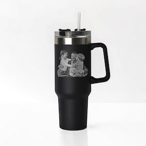 May include: Black stainless steel travel mug with a handle and a straw. The mug has a laser engraved image of a father and two children.