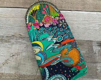 Op de afbeelding: Een kleurrijk, gepatroneerd stoffen brilletje met een messing sluiting. De etui heeft een grillig ontwerp met spiralen, sterren en bloemen in tinten blauw, groen, oranje, roze en geel.