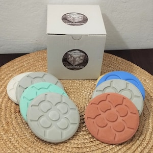 Può includere: Un set di sei sottobicchieri rotondi con colori e design diversi. I sottobicchieri sono realizzati in un materiale testurizzato e hanno un design in rilievo. I sottobicchieri sono confezionati in una scatola bianca con il nome dell'azienda "Yumilab Deco & Design" e l'indirizzo del sito web "www.yumilab.com".