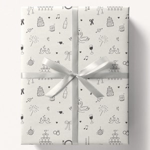 May include: A white gift box with a silver ribbon. The box is wrapped in white paper with a black and white pattern of wedding-themed illustrations, including cake, swans, rings, and champagne glasses.