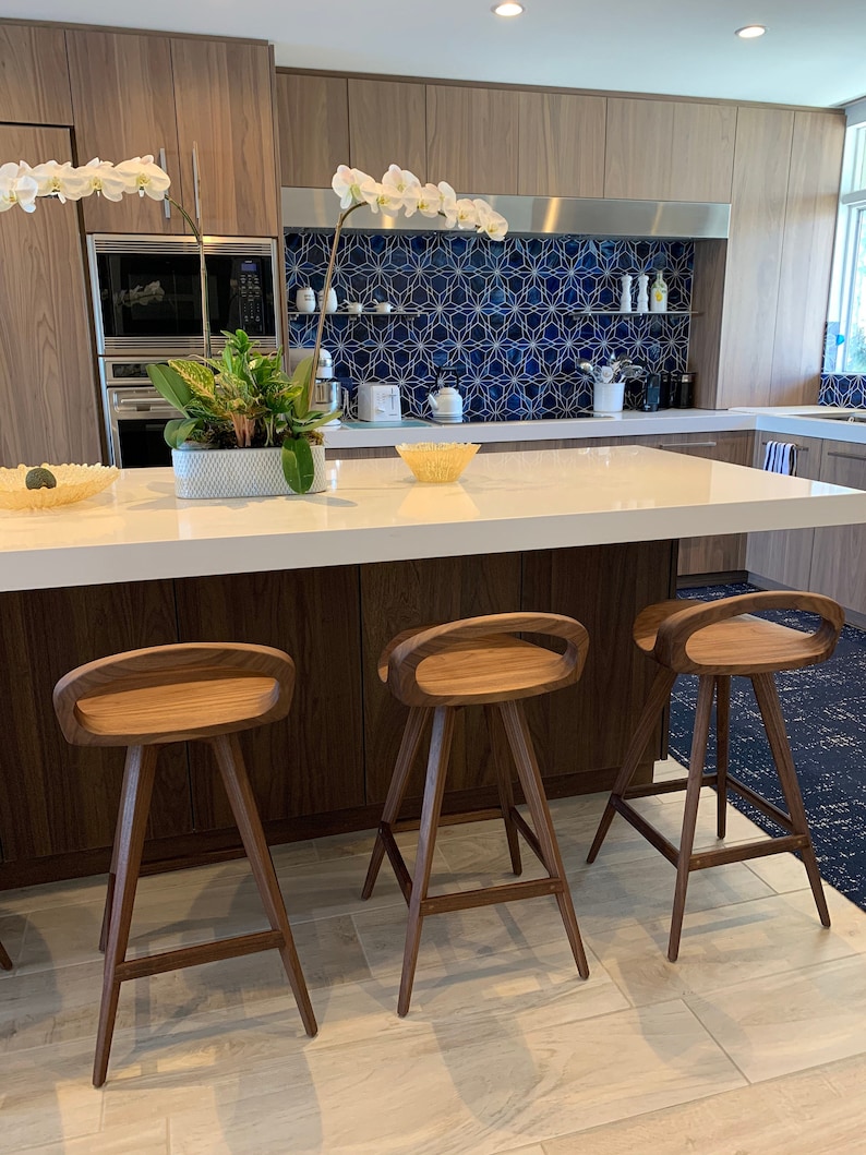 photo of three modern swivel counter stools surrounding a modern kitchen island, made of solid walnut, made in the USA by Marco Bogazzi