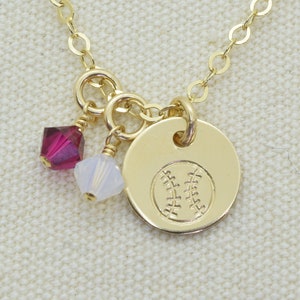May include: Gold necklace with a baseball charm and two small crystal beads. The beads are red and white.