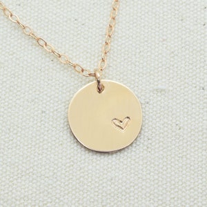 May include: A gold necklace with a round pendant featuring a small heart design.