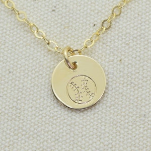 May include: A gold chain necklace with a small round pendant featuring a baseball design.