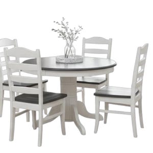 May include: A white and gray round dining table with four matching chairs. The table has a dark gray top and a white pedestal base. The chairs have white frames and dark gray seats. A vase of decorative branches sits on the table.