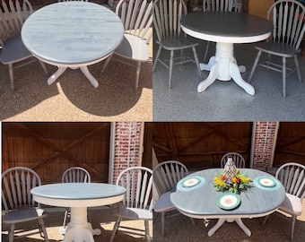 May include: A gray and white round table with four chairs. The table has a white pedestal base and the chairs have a spindle back.