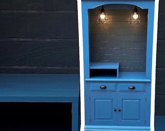 May include: A tall, blue cabinet with two doors and two drawers. The cabinet has a shelf and two light fixtures with cage-style shades.