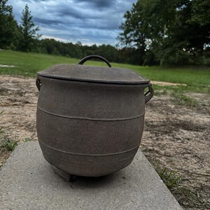 Caldero antiguo de hierro fundido: Olla para frijoles de tres patas con tapa, marcada con la inscripción "Gate" del siglo XIX.