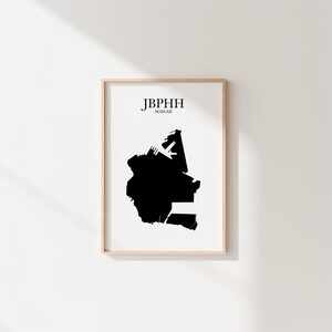 May include: A framed print with a black silhouette of a landmass, possibly a map, on a white background. The text "JBPHH HAWAII" is printed at the top in a simple font. The frame is a light wood colour.