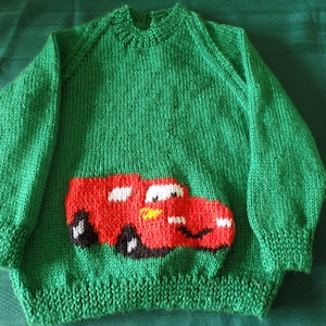 Hand knitted jumper featuring a big red car with a smiley face, made to order and available sizes 2 to 6
